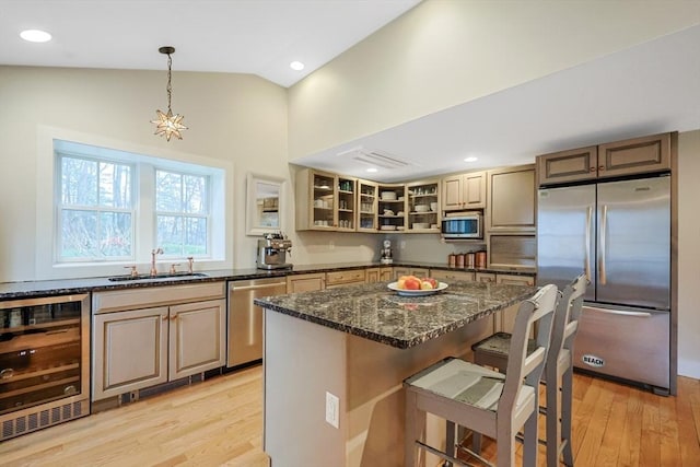 kitchen featuring appliances with stainless steel finishes, a sink, lofted ceiling, wine cooler, and a breakfast bar area