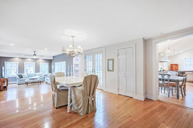dining room featuring baseboards, light wood-type flooring, vaulted ceiling, and ceiling fan with notable chandelier