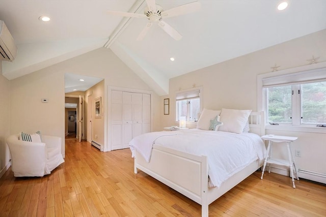 bedroom featuring light wood-type flooring, a closet, baseboard heating, a wall mounted AC, and lofted ceiling
