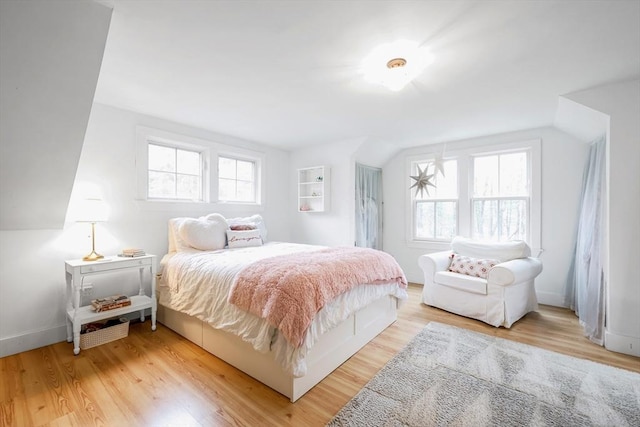 bedroom with light wood-style floors, baseboards, and vaulted ceiling