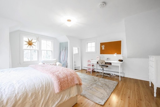 bedroom featuring baseboard heating, wood finished floors, baseboards, and vaulted ceiling