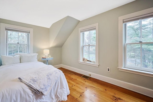bedroom with visible vents, baseboards, vaulted ceiling, and light wood-style floors