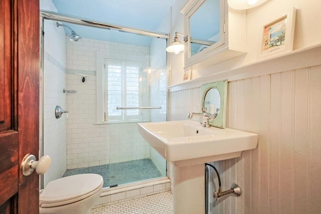 full bath with a shower stall, toilet, a wainscoted wall, and tile patterned floors