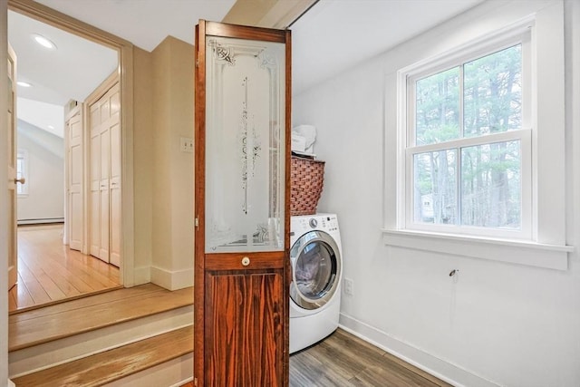 clothes washing area featuring washer / clothes dryer, baseboards, laundry area, wood finished floors, and a baseboard heating unit