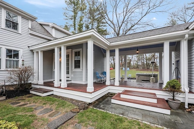 view of exterior entry featuring a porch and a shingled roof