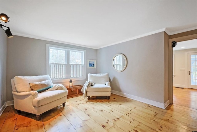 sitting room featuring light wood-style floors, crown molding, baseboards, and plenty of natural light
