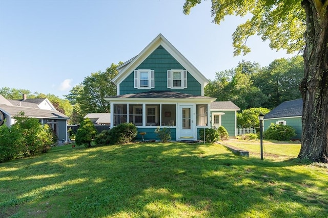 view of front of property featuring a front yard, a sunroom, and fence