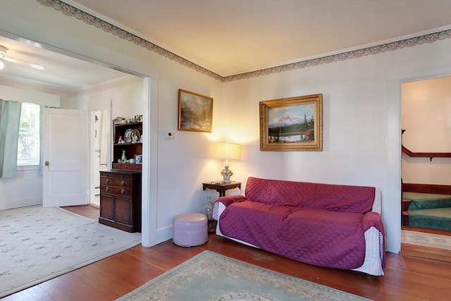 sitting room with baseboards, a ceiling fan, ornamental molding, wood finished floors, and stairs