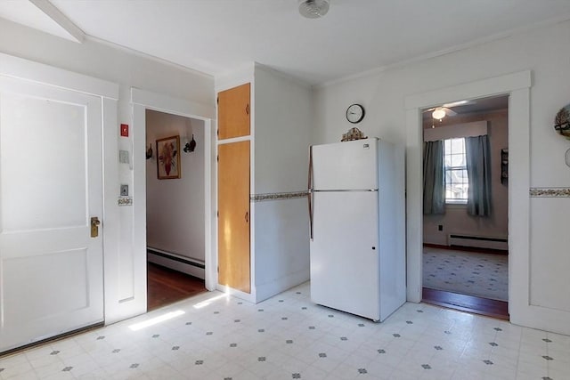 kitchen with light floors, a baseboard radiator, and freestanding refrigerator