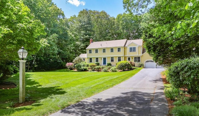 colonial-style house featuring a garage and a front yard