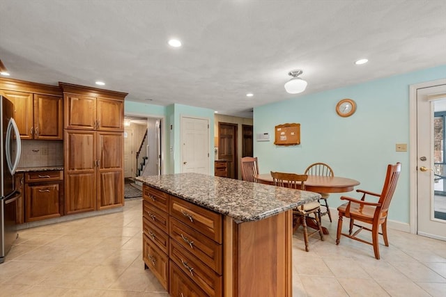12 Checkerberry Cir, Sudbury, MA 01776 - kitchen featuring brown cabinets, dark stone counters, light tile patterned floors, freestanding refrigerator, and recessed lighting