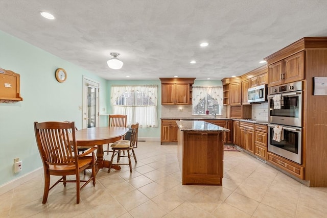 12 Checkerberry Cir, Sudbury, MA 01776 - kitchen with appliances with stainless steel finishes, brown cabinets, tasteful backsplash, recessed lighting, and a center island