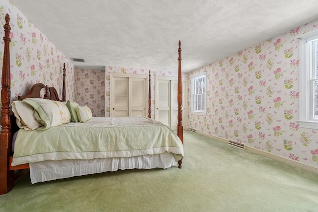 12 Checkerberry Cir, Sudbury, MA 01776 - bedroom featuring wallpapered walls, carpet floors, two closets, and a textured ceiling