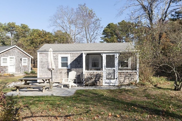 back of house with an outbuilding, a lawn, and a patio