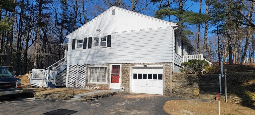 view of front of property with stairway, stone siding, a garage, and driveway