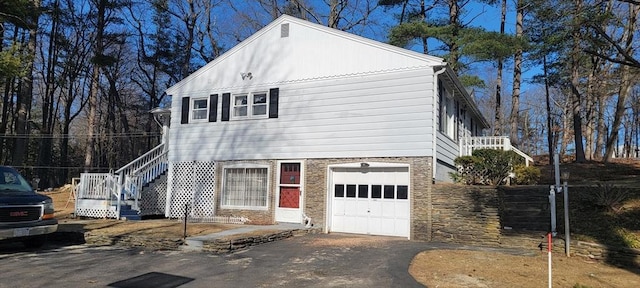view of front of property with stairway, stone siding, a garage, and driveway