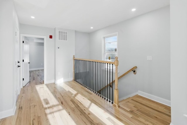 hall with an upstairs landing, wood finished floors, baseboards, and recessed lighting