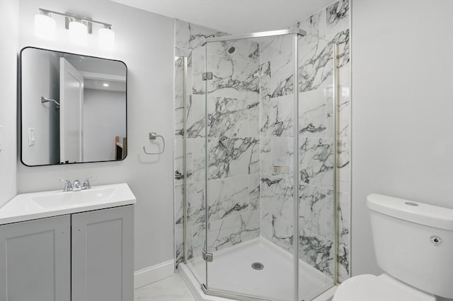 full bath featuring toilet, a marble finish shower, vanity, and baseboards