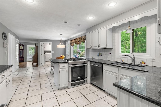 5 Hansen Ave, Burlington, MA 01803 - kitchen with stainless steel appliances, a sink, a peninsula, light tile patterned floors, and plenty of natural light