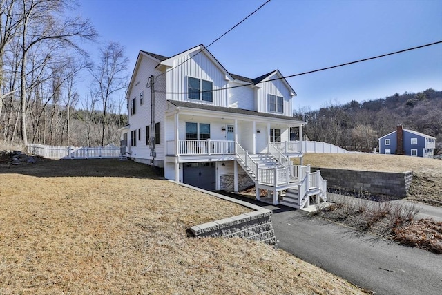 view of front of home with board and batten siding, fence, stairway, covered porch, and an attached garage