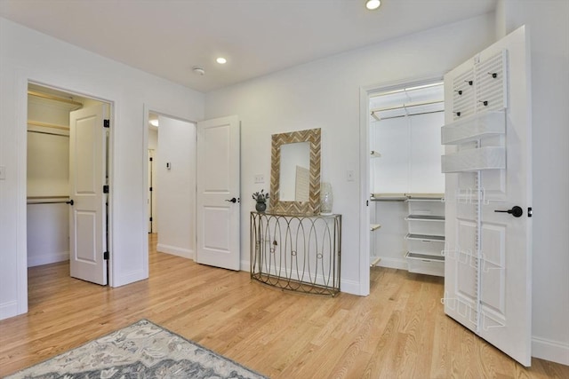 bedroom featuring light wood-type flooring, recessed lighting, a closet, baseboards, and a spacious closet