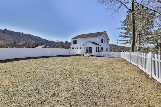 rear view of house with a lawn and a fenced backyard