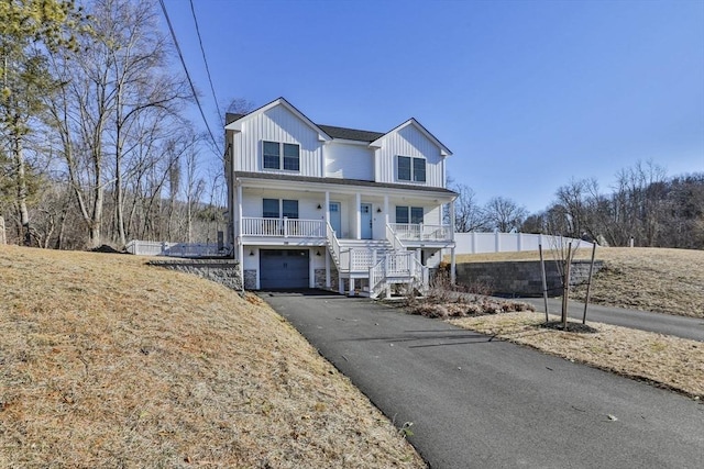 view of front of home featuring aphalt driveway, stairway, board and batten siding, covered porch, and an attached garage