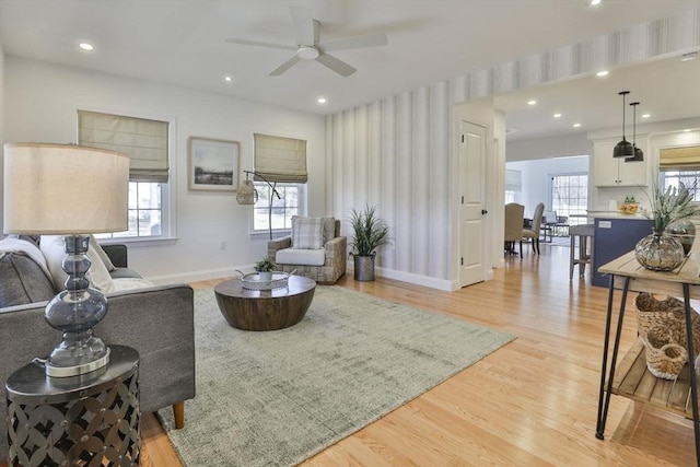 living area with a ceiling fan, recessed lighting, light wood-style floors, and baseboards