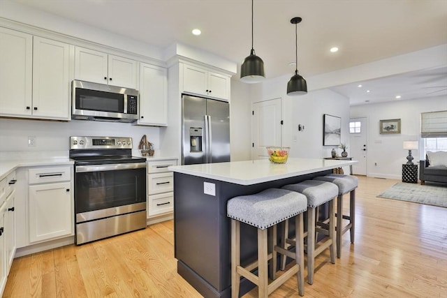 kitchen with a kitchen breakfast bar, light wood-style flooring, light countertops, and stainless steel appliances