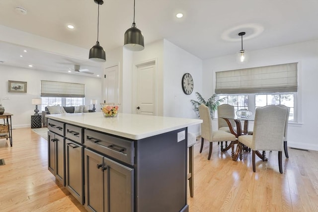 kitchen with a kitchen island, decorative light fixtures, light countertops, recessed lighting, and light wood-style flooring