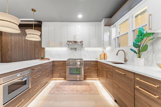 kitchen featuring appliances with stainless steel finishes, decorative light fixtures, white cabinetry, and sink