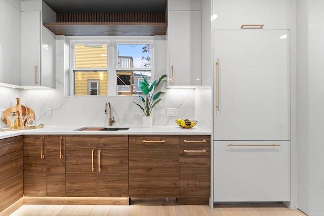 kitchen featuring light wood-type flooring, white refrigerator, white cabinets, and sink