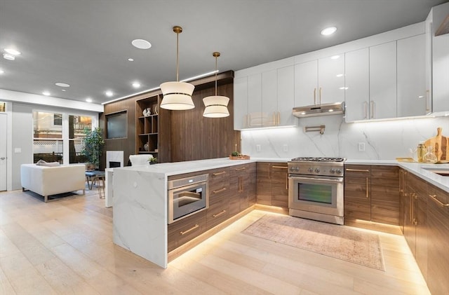 kitchen with light wood-type flooring, tasteful backsplash, stainless steel appliances, white cabinetry, and hanging light fixtures