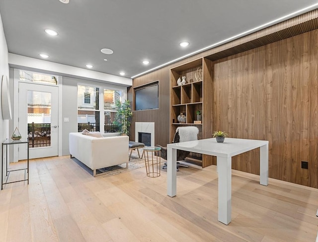 home office with built in shelves, light hardwood / wood-style flooring, and wood walls