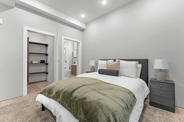 bedroom featuring connected bathroom, a closet, and light hardwood / wood-style flooring