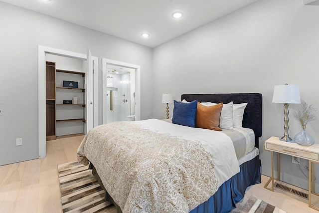 bedroom featuring a spacious closet and light hardwood / wood-style flooring