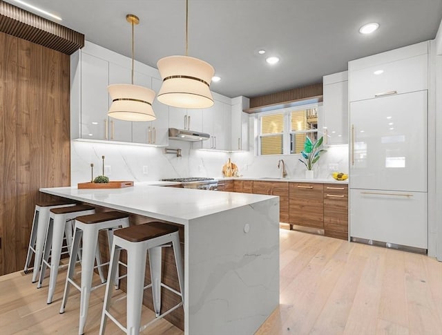 kitchen with white cabinetry, a breakfast bar, light hardwood / wood-style floors, and decorative light fixtures