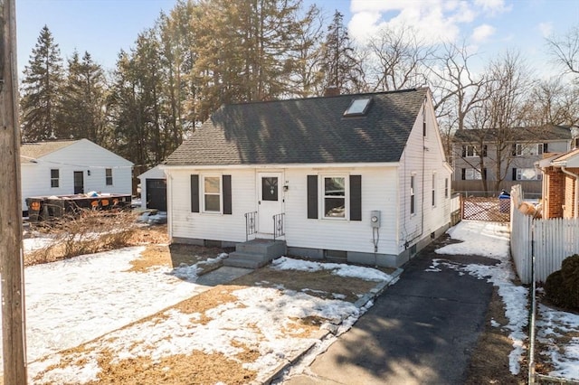 cape cod-style house with a shingled roof, fence, and a chimney