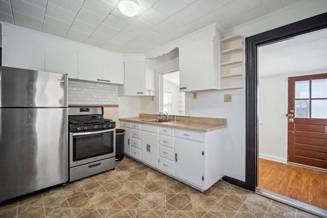 kitchen with open shelves, stainless steel appliances, light countertops, white cabinetry, and a sink