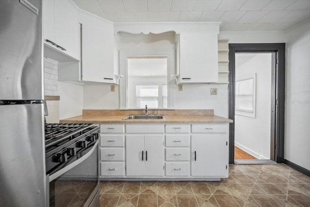 kitchen with light countertops, appliances with stainless steel finishes, a sink, and white cabinets