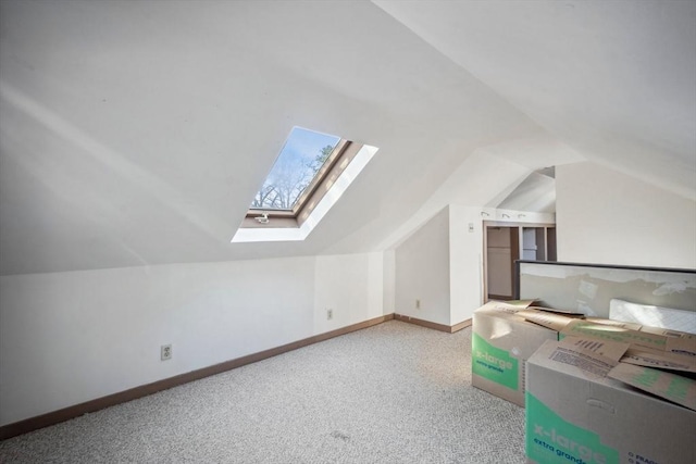 additional living space with carpet, vaulted ceiling with skylight, and baseboards