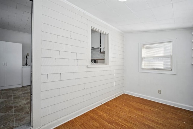 spare room with ornamental molding, wood finished floors, and baseboards