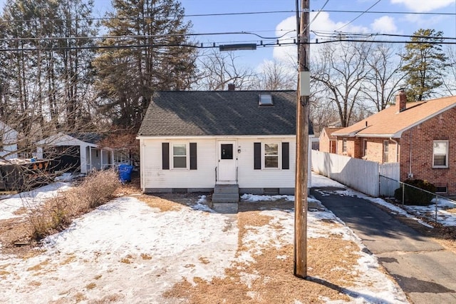 view of front of house with entry steps, roof with shingles, and fence