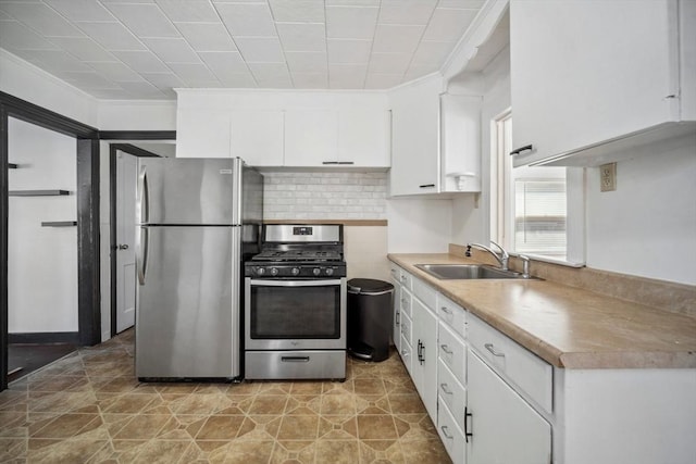 kitchen with light countertops, backsplash, appliances with stainless steel finishes, white cabinetry, and a sink