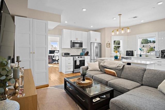 living room featuring a chandelier, light hardwood / wood-style floors, and sink