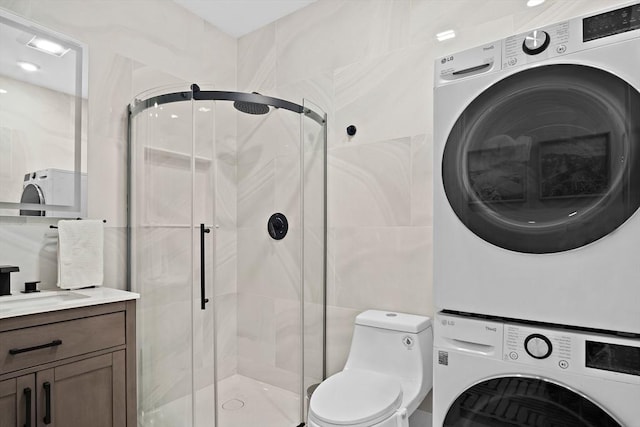 bathroom with vanity, toilet, an enclosed shower, and stacked washer and clothes dryer