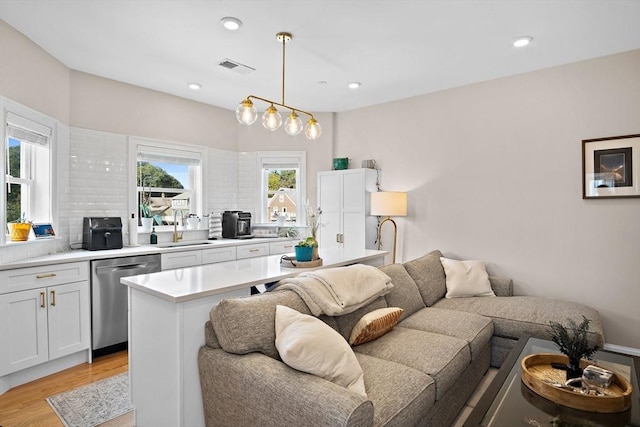 kitchen featuring stainless steel dishwasher, plenty of natural light, sink, and hanging light fixtures