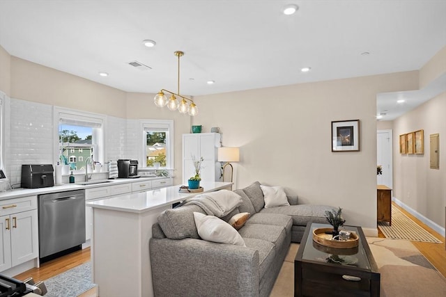 living room with an inviting chandelier, sink, and light hardwood / wood-style flooring