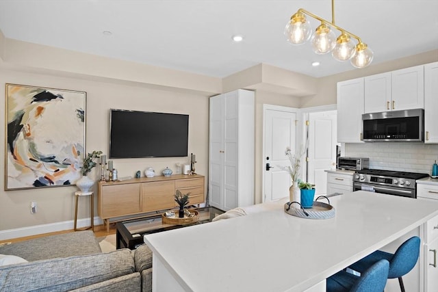 kitchen featuring appliances with stainless steel finishes, a center island, decorative light fixtures, and white cabinetry