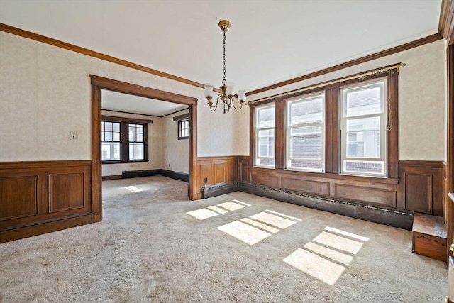 unfurnished dining area featuring ornamental molding, a wainscoted wall, and carpet floors